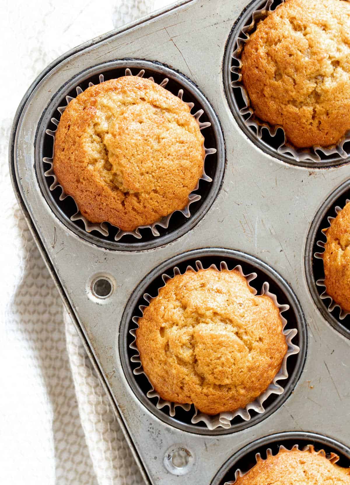 Baked pumpkin banana muffins in the metal tin on a white cloth.