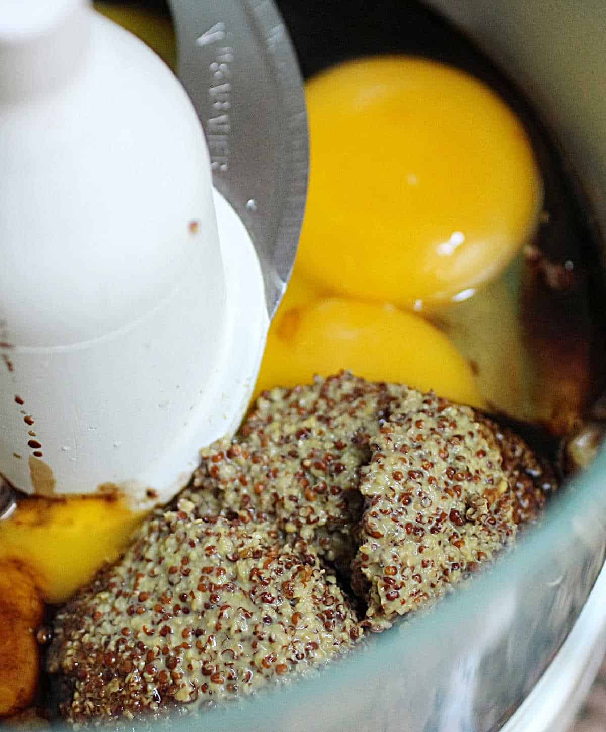 Grainy mustard and eggs in the bowl of a food processor. Close up image. 