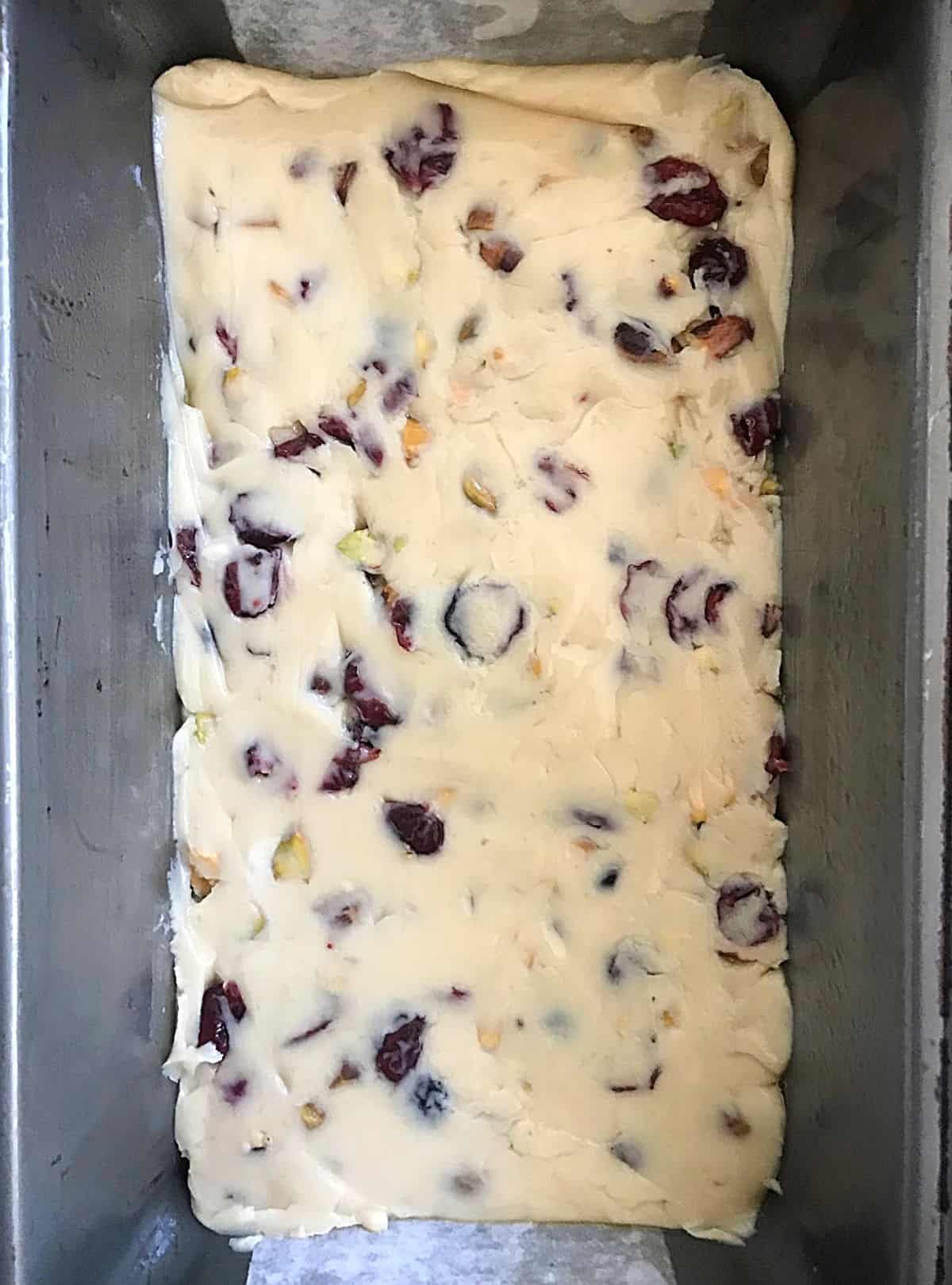 Top view of white chocolate cranberry pistachio fudge in a metal loaf pan. 