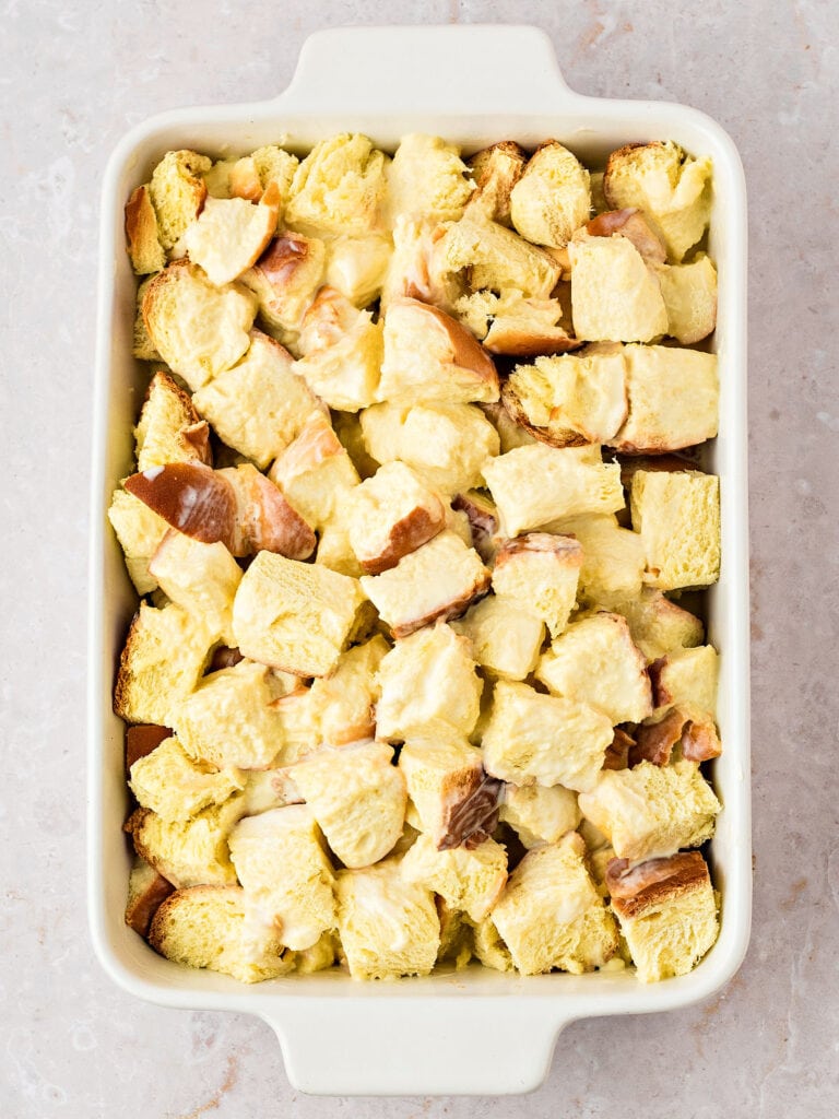 Soaked brioche bread cubes in a rectangular white dish. Light gray background.
