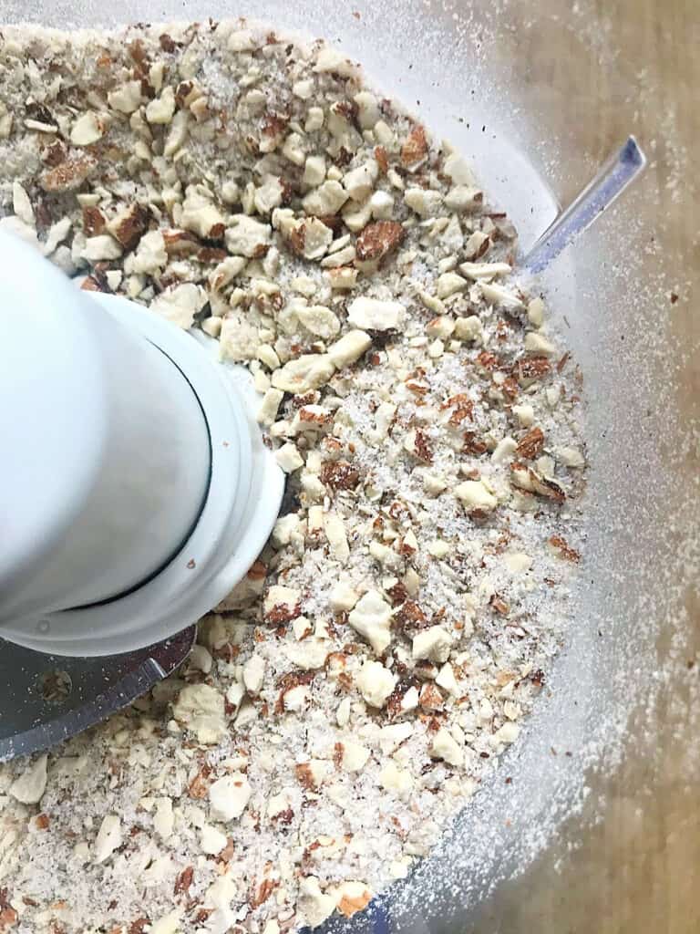 Coarsely ground almonds and sugar in the bowl of a food processor.