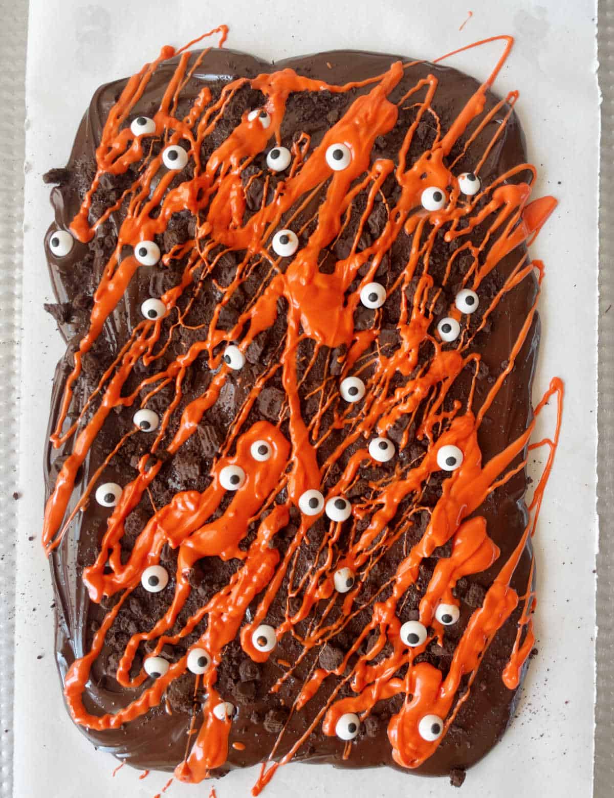 Halloween bark with dark and orange colored chocolates, crushed chocolate wafers, and candy eyes. Top view.