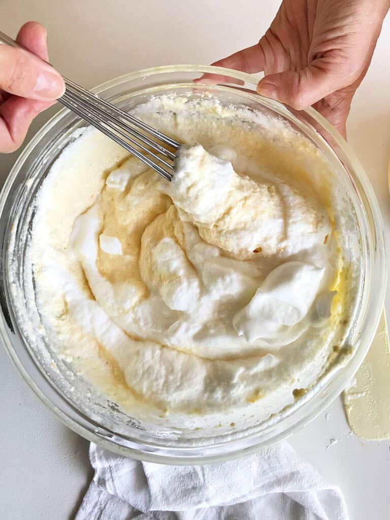 Folding egg whites into ricotta cheesecake batter. Glass bowl, top view.