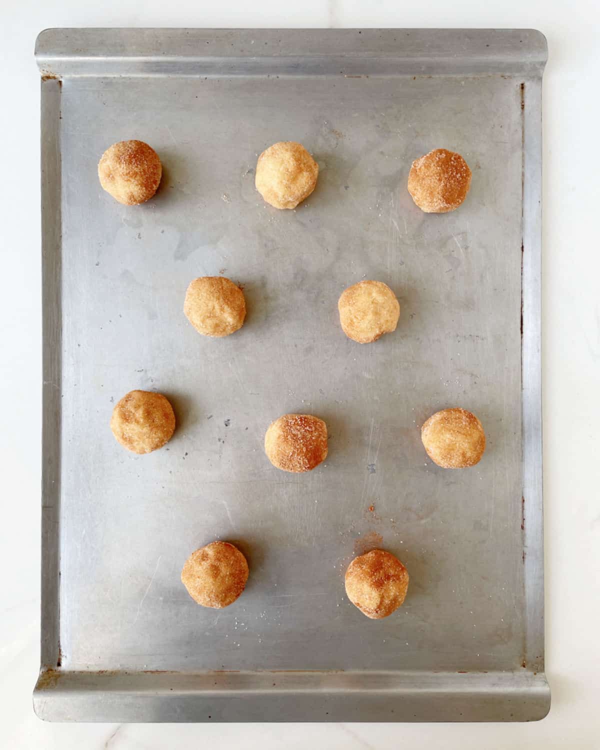Metal pan with raw balls of snickerdoodle cookies. View from above.