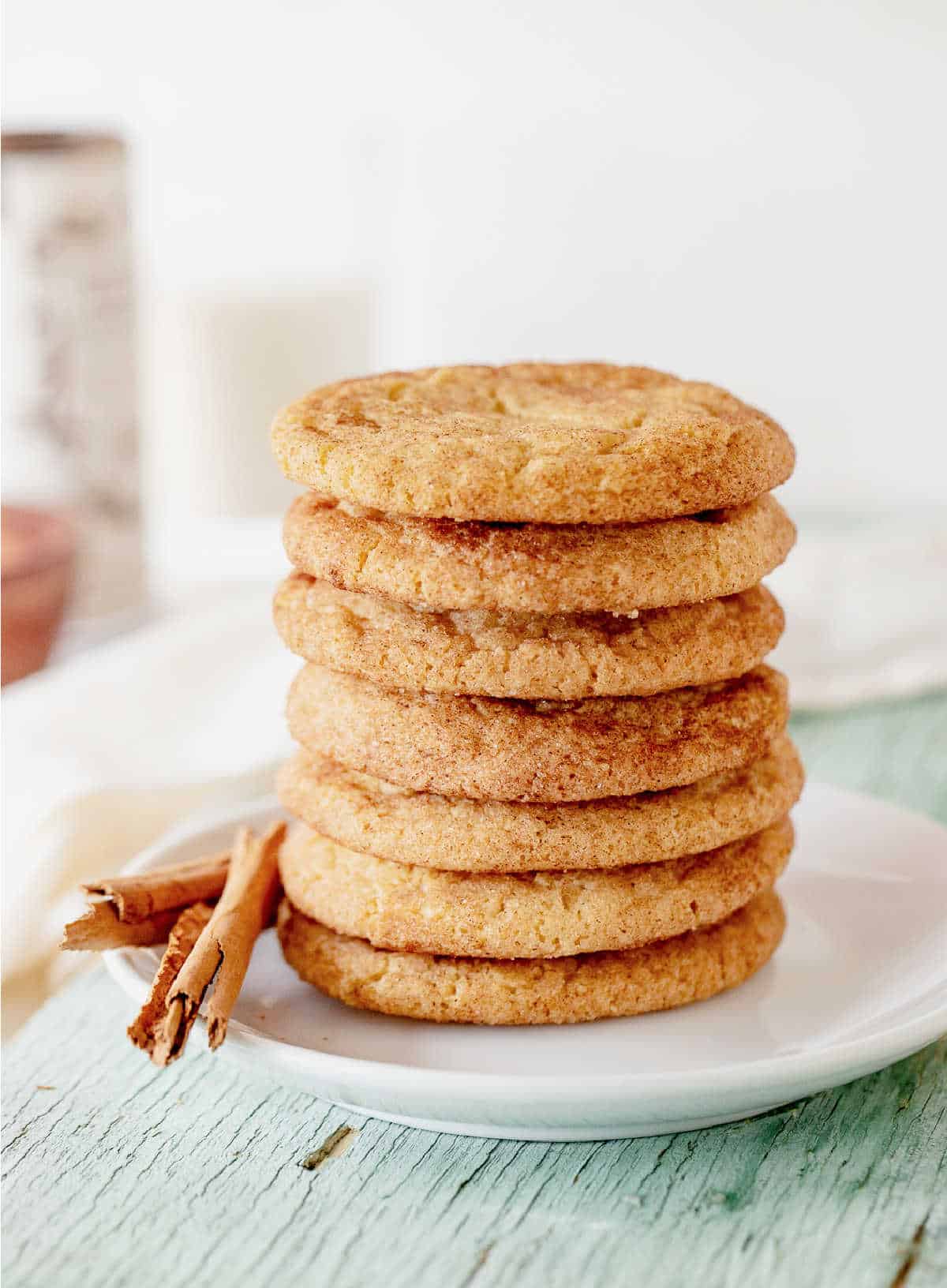 Stacked snickerdoodle cookies on a white plate on a green wooden board. White background.