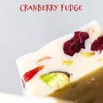 Red text overlay over close up image of pistachio cranberry white fudge with a grey background.