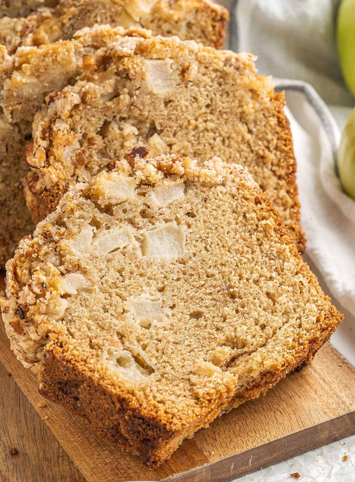 Close up of slices of apple bread with streusel on a wooden board.