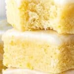 Brown, white and teal text overlay on stack of glazed lemon brownies.