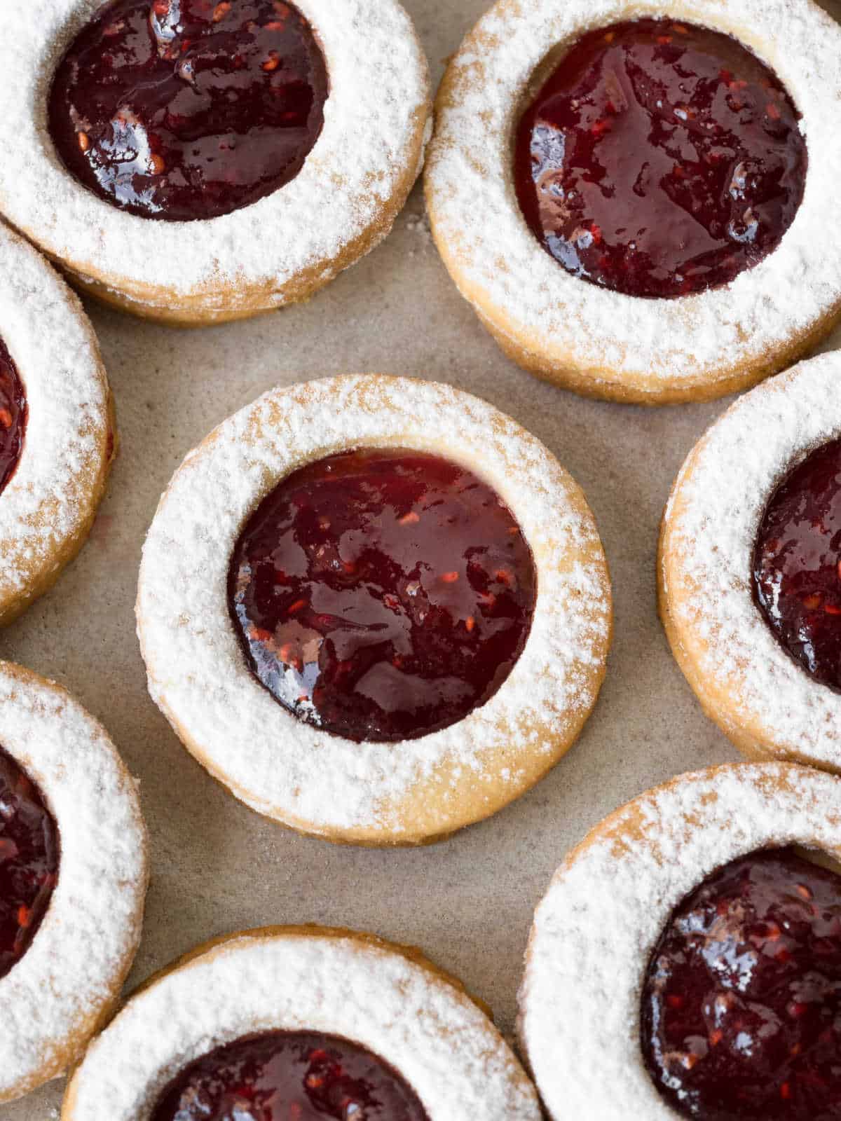 Top view of raspberry linzer tart cookies close up on a beige surface. 