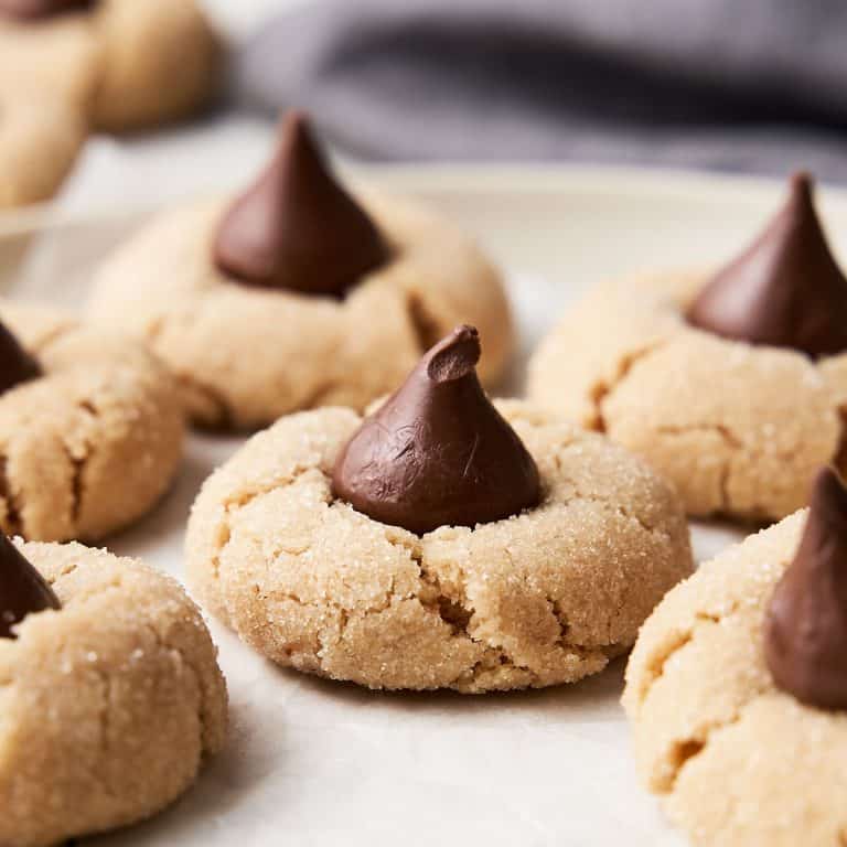 Peanut butter blossom cookies close up on a cream colored plate with a grey cloth in the background.