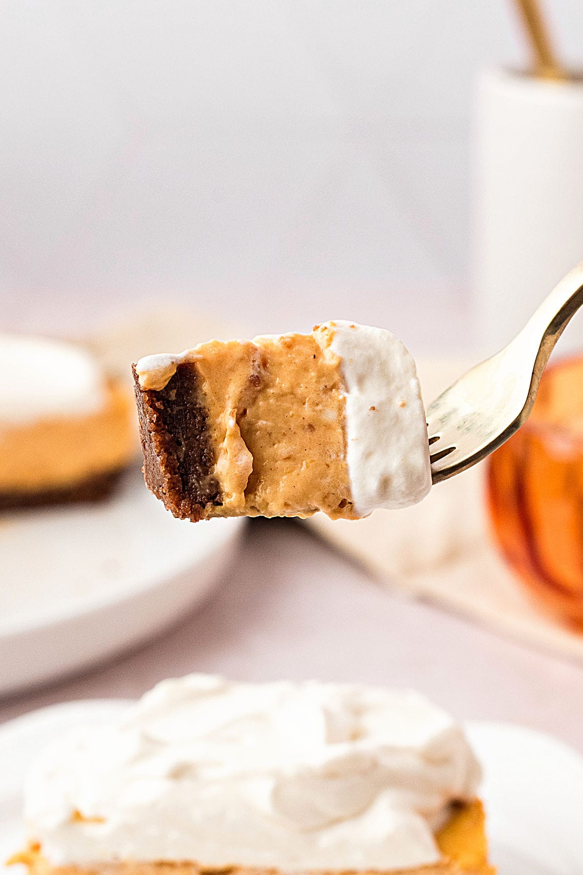 Forked bite of chocolate crust pumpkin cream cheesecake. Light gray background.