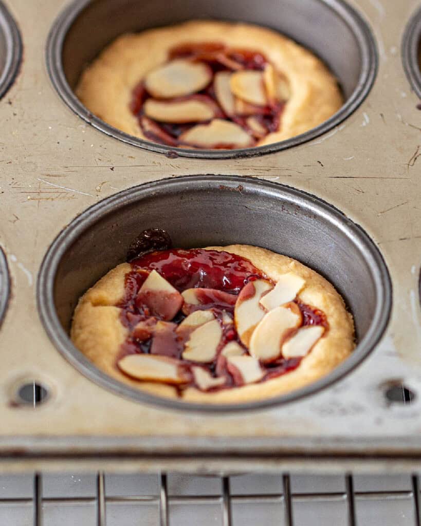 Metal muffin pan with raspberry almond shortbread tarts.