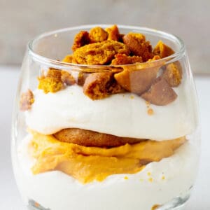 Close up of layered pumpkin cream trifle in a glass. Gray background.