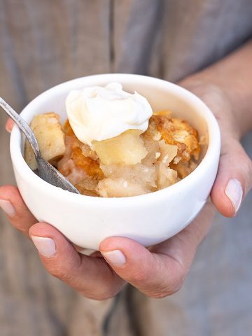 Spoon with vanilla pudding, baby food in hand on a white backgro