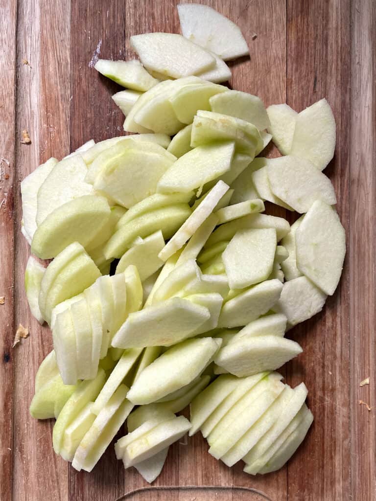 Wooden board with peeled apple slices.
