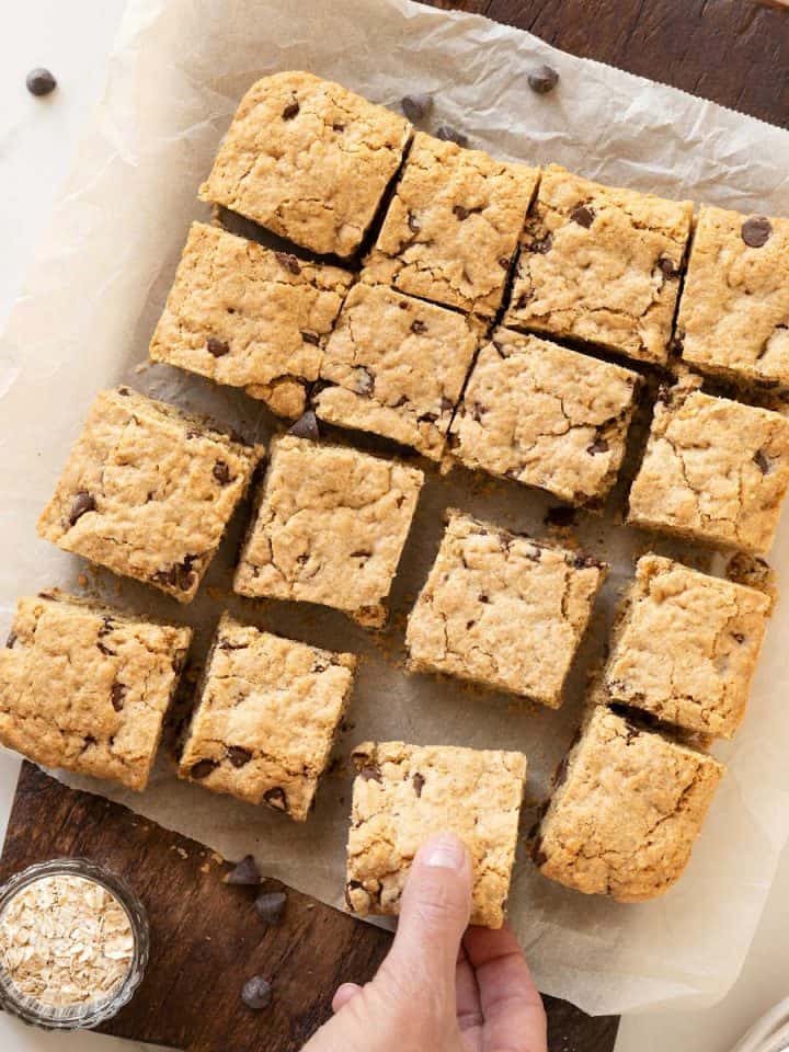 Bars of oatmeal chocolate chip cookie dough on parchment paper and a wooden board.