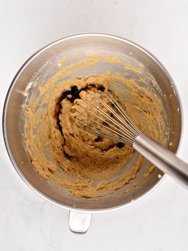 Whisk inside a metal bowl with butter, brown sugar and vanilla mixture.