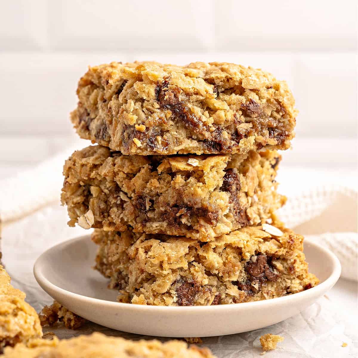 Stack of three oatmeal chip bars on a white plate. Tile background.