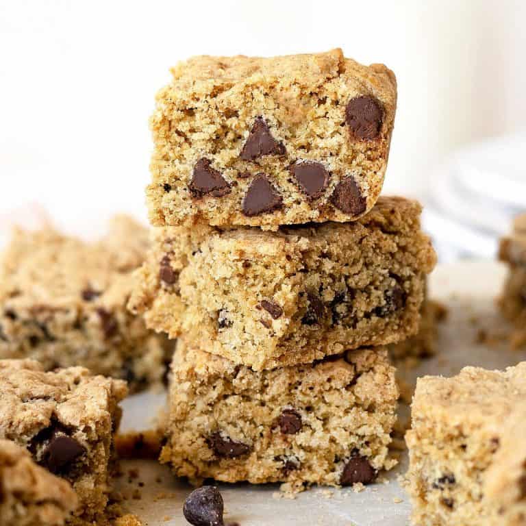 Close up stack of chocolate chip oatmeal cookie bars surrounded by more squares. White background.
