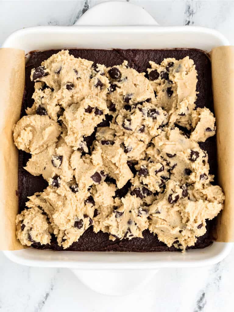 Chocolate chip cookie dough over brownie batter. White dish.