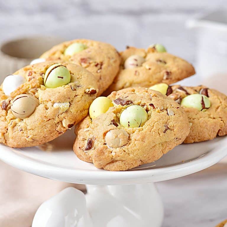 Several mini egg cookies on a white plate with a bunny. Grey background.