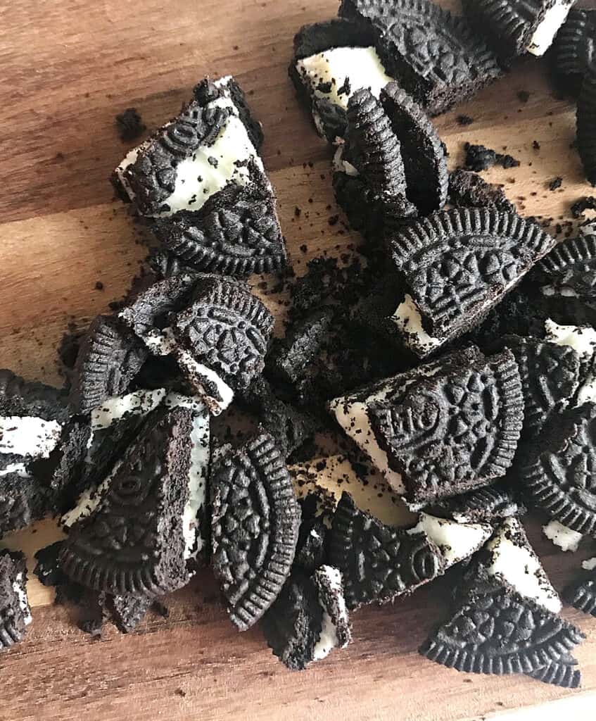 Chopped Oreo cookies on a wooden board.