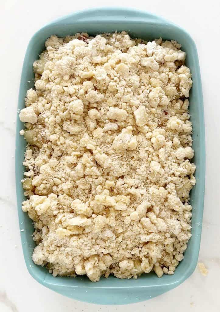 A rectangular ceramic light blue baking dish with pineapple dump cake before baking. White marble surface.