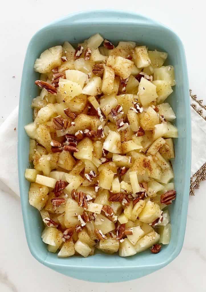 Pecan and pineapple filling in a light blue rectangular baking dish on a white marble surface.
