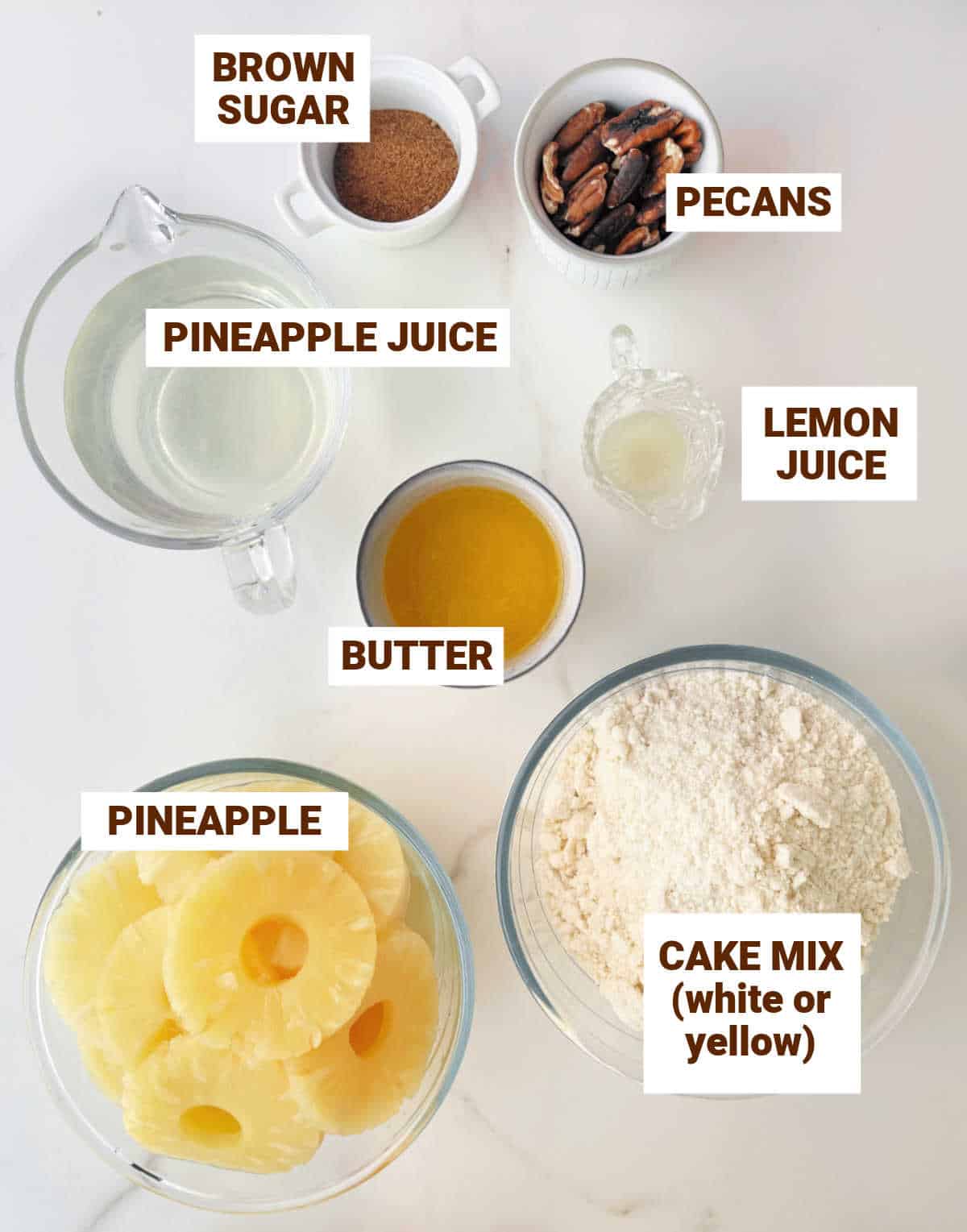 White marble surface with bowls containing ingredients for pineapple dump cake including pecans, butter, lemon juice, cake mix, brown sugar.