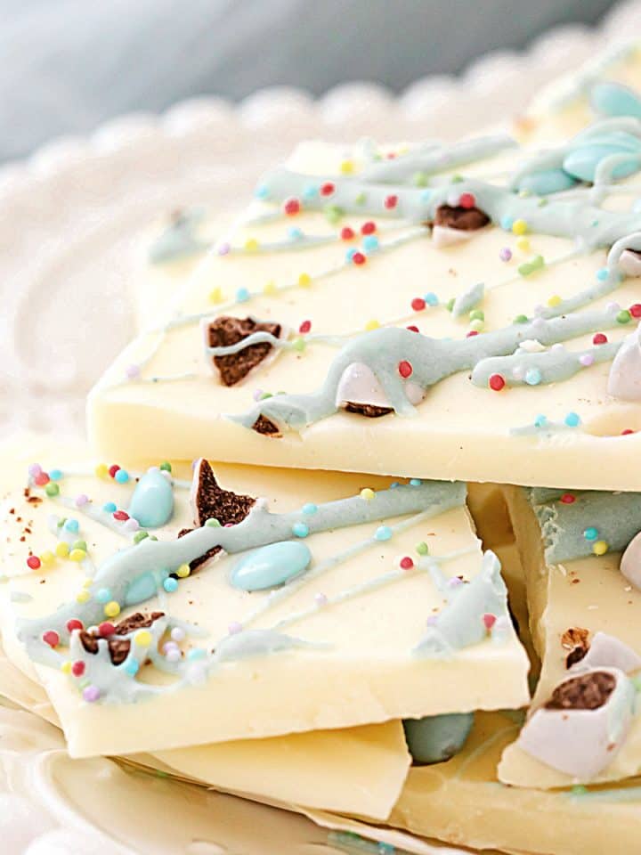 Close up of white chocolate Easter bark pieces on a white plate. Light blue cloth in the background.