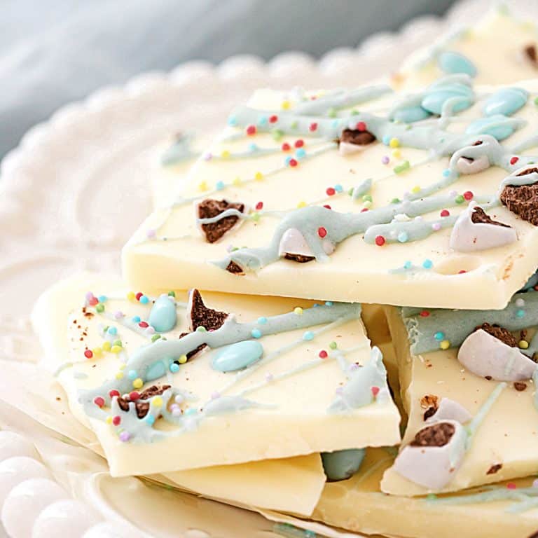 Close up of white chocolate Easter bark pieces on a white plate. Light blue cloth in the background.