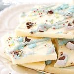 Light blue and white text overlay on close up of white chocolate Easter bark pieces on a white plate.