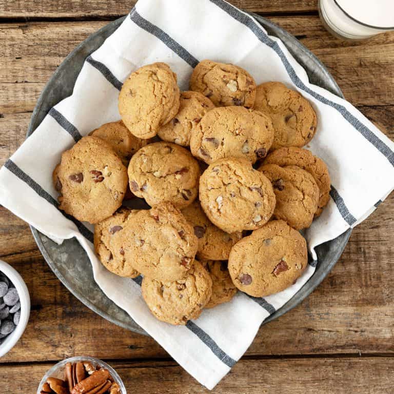 Top view of pile of chocolate chip cookies on a striped cloth set on a wooden surface.