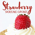 Red text overlay on cream-topped vanilla strawberry cupcake. Beige paper liner. White background.