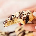 Pink, brown and white text overlay on bitten chocolate-drizzled almond cookies.