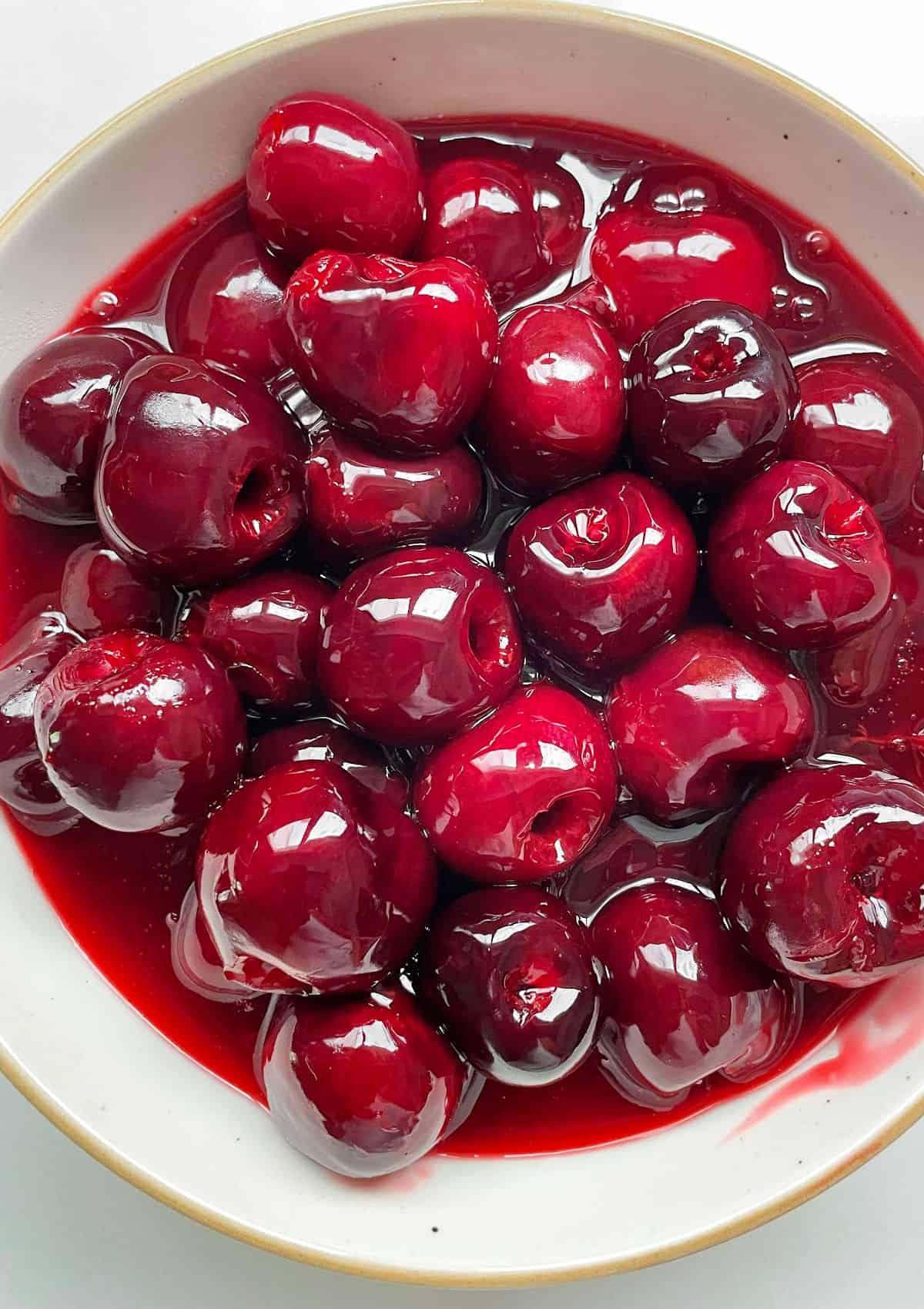 White bowl with fresh cherry sauce and topping.