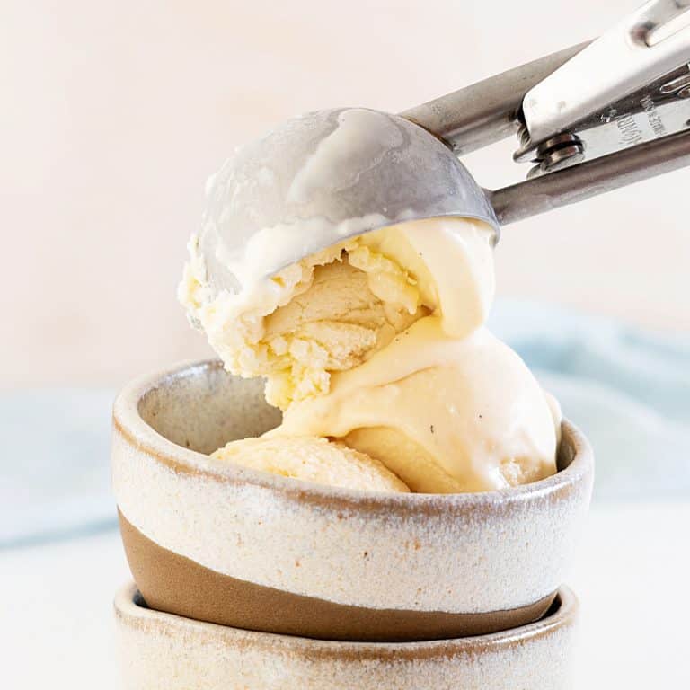 Scooping vanilla ice in a beige bowl. Pink and light blue background.