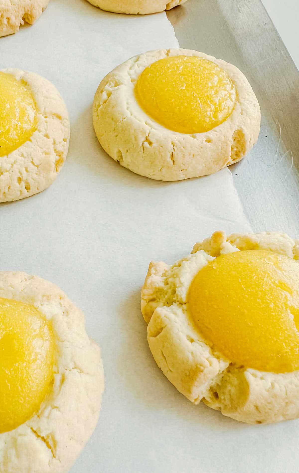 Very close up image of lemon thumbprint cookies on white parchment paper. 