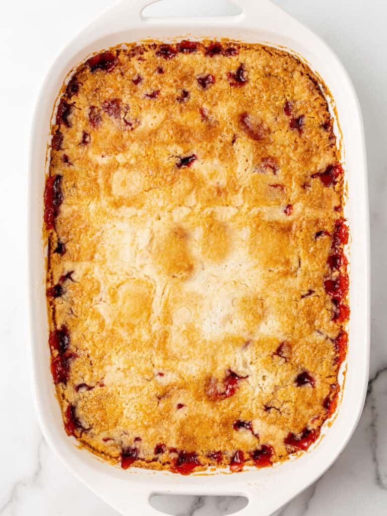 Baked cobbler with cake mix in a white ceramic rectangular dish.