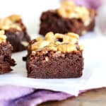 Close up walnut brownie squares on a white and purple surface.