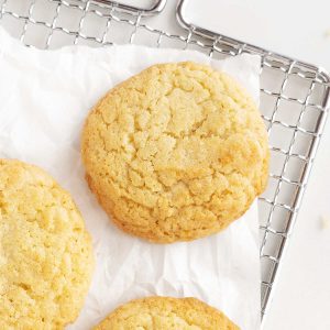 Wire rack with white paper and vanilla cookies on top.