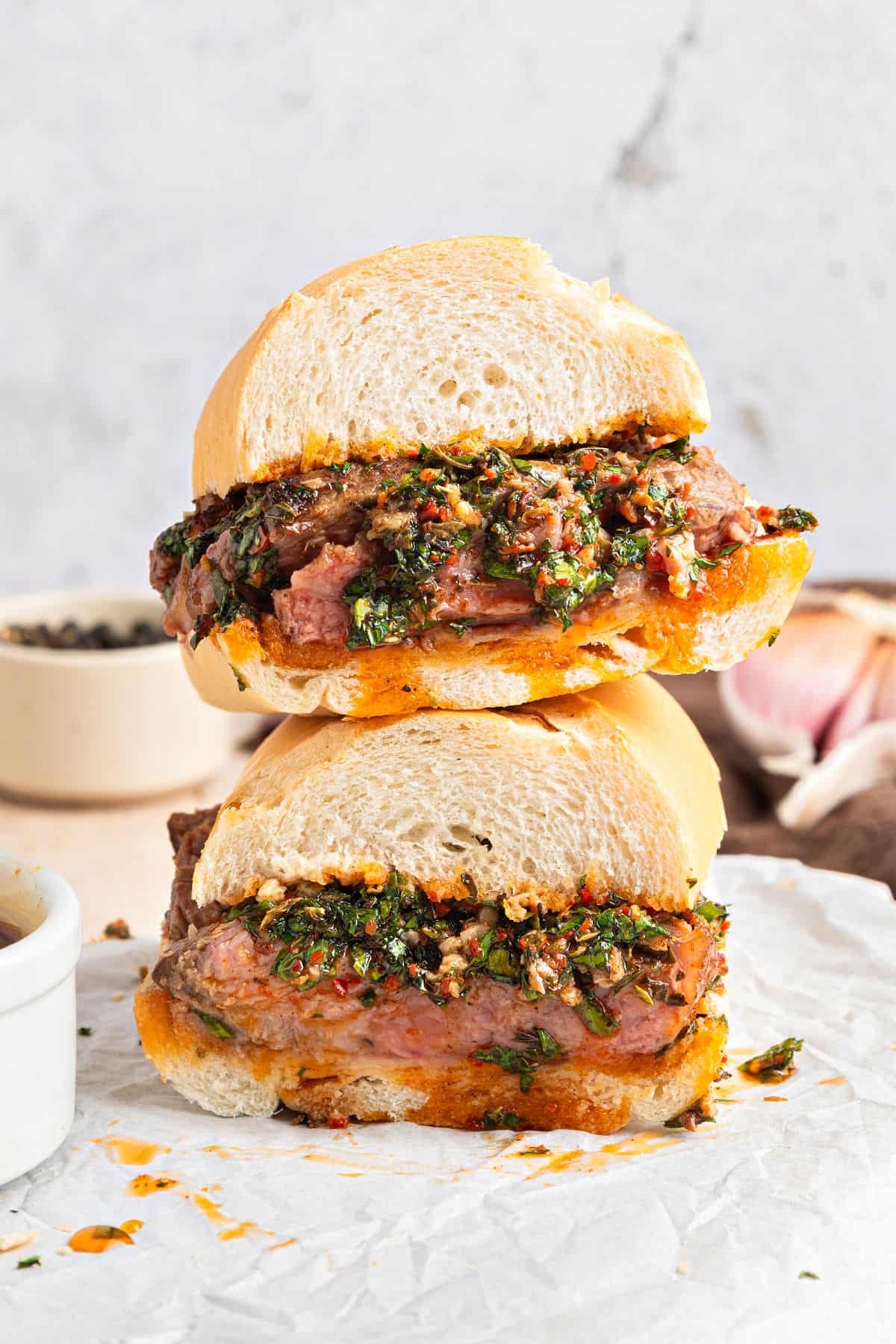 Marinated Steak and Chimichurri Sliders Stack of chimichurri steak sandwich on white parchment. Light gray background.