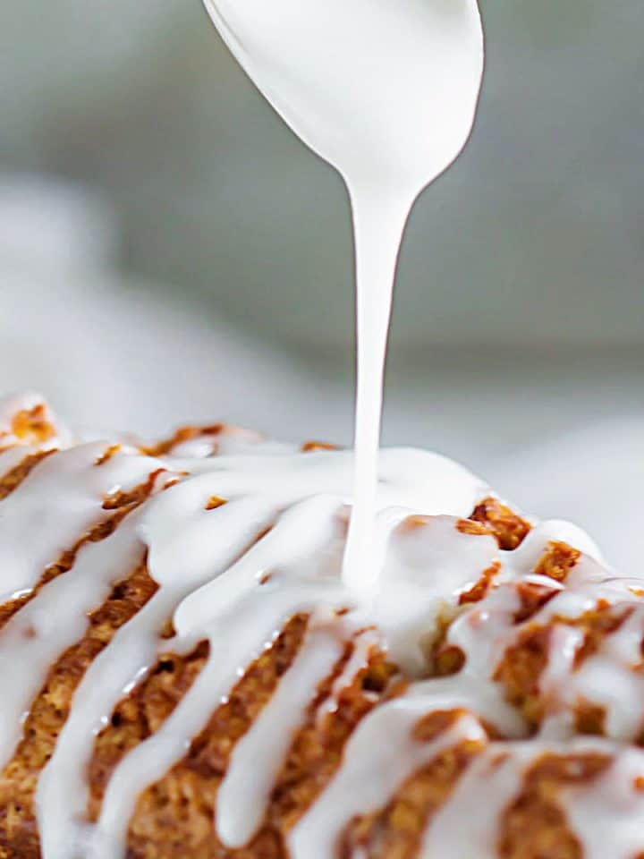 Close up image of powdered sugar glaze being drizzled on a loaf cake.