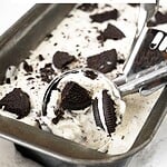Red, brown and white text overlay on metal loaf pan with Oreo ice cream and scoop.