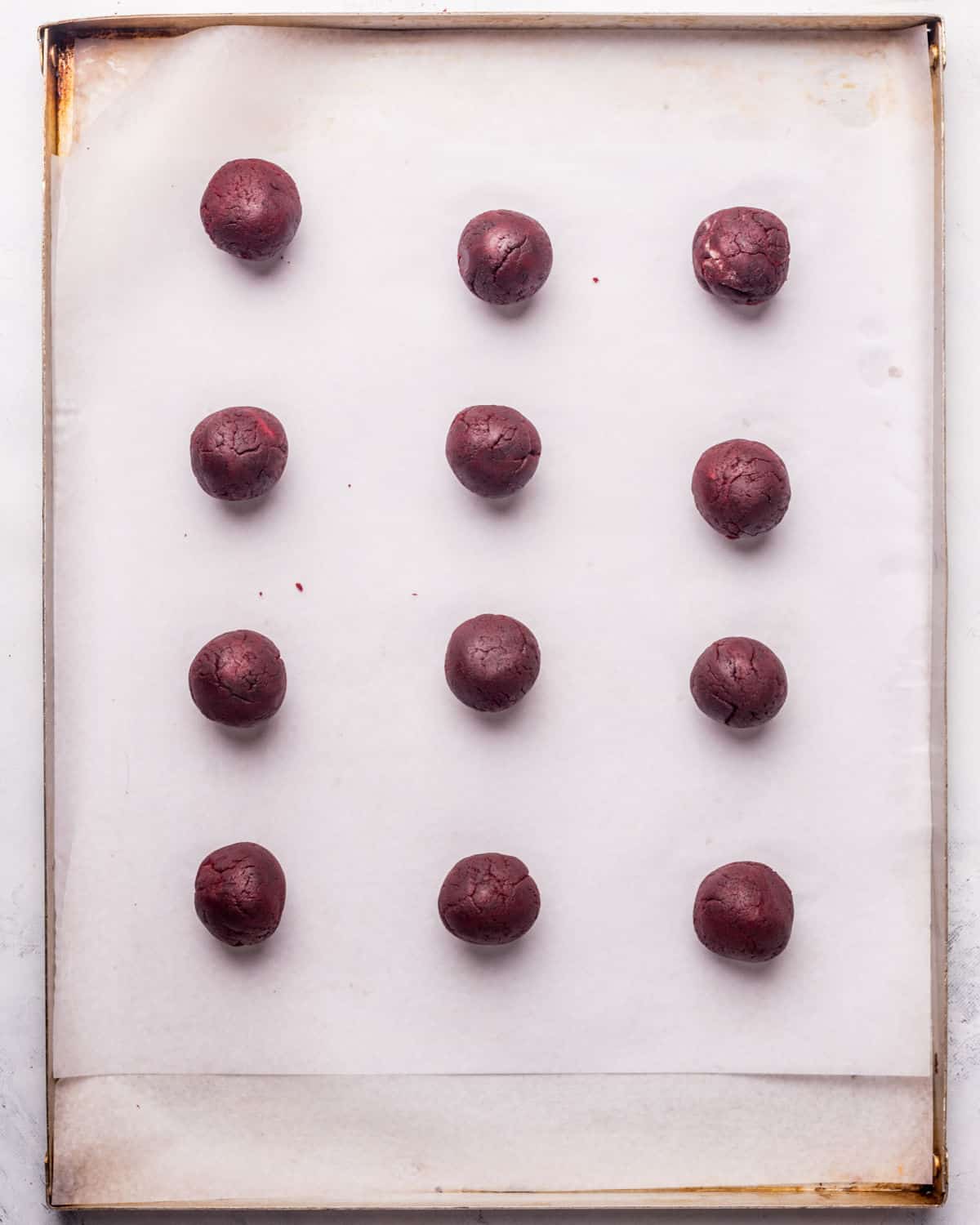 Top view of red velvet cake balls on parchment paper on a baking sheet.