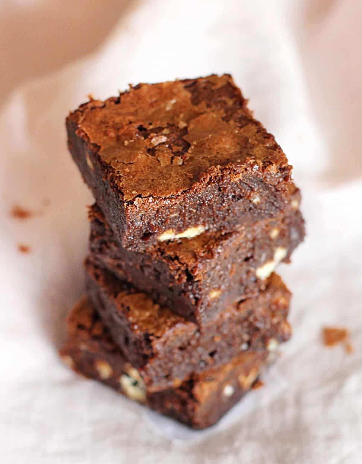 Stack of chocolate brownie squares on a light pink napkin.