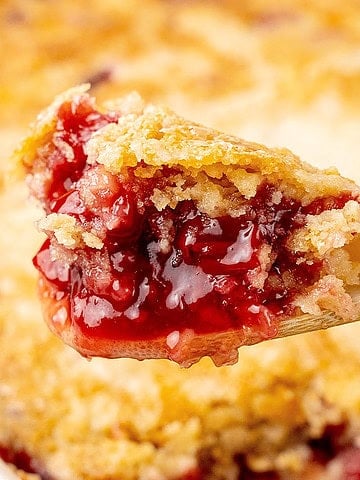 Close up of scooped portion of cherry dump cake on a wooden spoon.