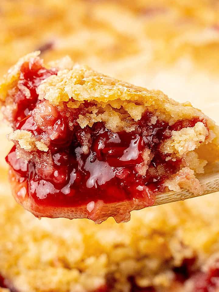 Close up of scooped portion of cherry dump cake on a wooden spoon.