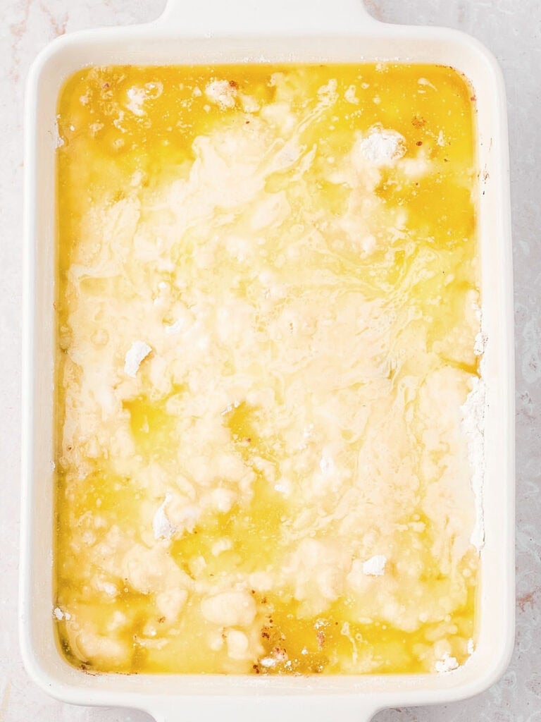 Melted butter topped cake mix in a white baking dish.