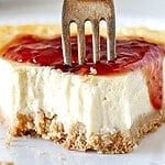 Brown, red and white text overlay on piece of bitten cheesecake.